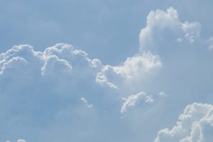 Фотография голубого неба с большими, пышными кучевыми облаками. Облака имеют ярко-белый цвет и сложную структуру.