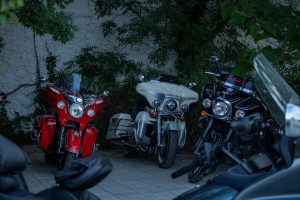 Фотография трех мотоциклов Harley-Davidson, стоящих на парковке возле здания. Мотоциклы имеют разные цвета: красный, черный и серебристый.
