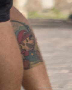 Фото тату: детализированная татуировка Марио из Super Mario Bros на плече. Яркие цвета и проработанные детали создают реалистичный образ любимого персонажа.