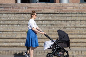 Фото татуировки на руке женщины, гуляющей с коляской. Рисунок выполнен в черном цвете и представляет собой абстрактный узор, сочетающийся с повседневным образом.