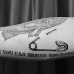 Фото тату: реалистичный рисунок булавки с надписью "ONLY YOU CAN DEFINE YOURSELF" на руке. Черно-белая татуировка с акцентом на самоопределение.