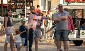 Фотография семьи на улице, у одного из мужчин на руке видна татуировка. Уличный снимок с татуировками.