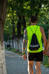 Фото тату на руке мужчины, занимающегося спортом на открытом воздухе. Видна яркая татуировка в стиле олдскул с цветами и узорами.