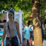 Фото тату на плече в уличной обстановке: реалистичный рисунок розы с черепом, выполненный в черно-серых тонах. Видна часть лица и волос девушки.