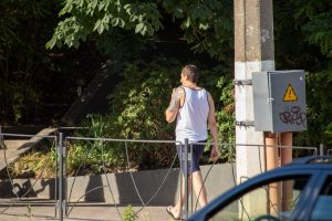 Фото мужчины с татуировкой на руке, идущего по улице. Татуировка выполнена в черно-серых тонах и имеет геометрический узор.