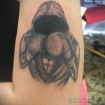 Фото тату на предплечье, изображающее фигуру в капюшоне и перчатках. Черно-белый рисунок с использованием техники дотворк и градиентов.