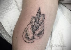 Черно-белая татуировка на предплечье с изображением боксерских перчаток. Лаконичный рисунок татуировки в стиле графика.