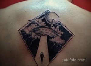 Фото чёрно-белой татуировки с изображением НЛО, похищающего человека. Детализированный рисунок на спине.