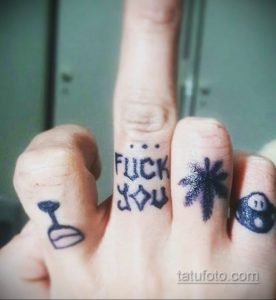 Фото тату: надпись 'FUCK YOU' и изображения на пальцах, включая череп и восьмерку для бильярда.