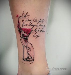 Фото тату: рисунок бокала вина с брызгами и надписью "Life is too short for cheap wine and slow days". Мотивационный дизайн на руке.
