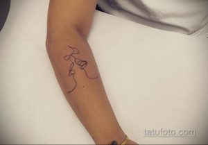 Фото тату: Изящная татуировка, изображающая лицо, выполненная одной непрерывной линией на руке. Минималистичный и современный дизайн.