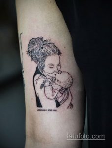 Фото тату на руке: изображение матери, держащей на руках ребенка. Рисунок выполнен в минималистичном стиле, с использованием тонких линий.