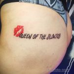 Фото татуировки с красными губами и надписью "QUEEN OF THE BLOWJOB" на боку. Смелый и откровенный рисунок.