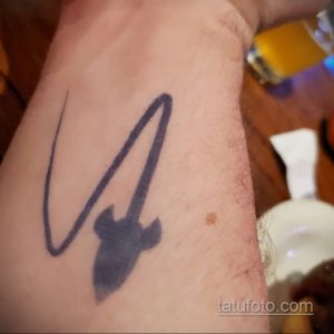 Фото тату на руке: абстрактный рисунок, изображающий след кометы или ракеты. Черно-серый рисунок татуировки.