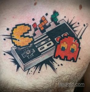 Фото тату на груди с изображением Pac-Man, геймпада и кубиков Рубика. Яркие цвета, динамичная композиция и пиксельный стиль.
