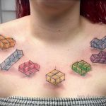 Фото тату на груди с изображением разноцветных кубиков, выполненных в стиле doodle. Легкий и игривый дизайн.