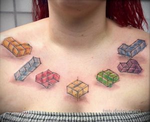 Фото тату на груди с изображением разноцветных кубиков, выполненных в стиле doodle. Легкий и игривый дизайн.