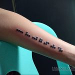Фото тату на предплечье, изображающее текст, написанный шрифтом Брайля. Минималистичный дизайн и скрытый смысл.