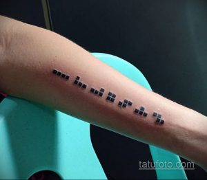 Фото тату на предплечье, изображающее текст, написанный шрифтом Брайля. Минималистичный дизайн и скрытый смысл.