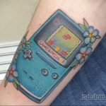 Фото тату Game Boy Color с играми и цветами, расположенное на предплечье, в ярких и красочных тонах.