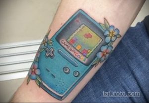 Фото тату Game Boy Color с играми и цветами, расположенное на предплечье, в ярких и красочных тонах.