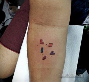 Фото тату с изображением нескольких пиксельных фигур из игры Тетрис, выполненных в разных цветах, на руке.