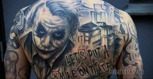 Фото татуировки на спине с изображением Джокера, городской пейзаж и надпись "Let's put a smile on that face".