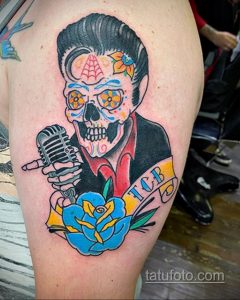 Фото тату Элвиса Пресли в стиле sugar skull на плече. Яркий и красочный рисунок татуировки с использованием цветов и узоров.