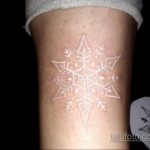 Фото тату на руке: белая снежинка, выполненная техникой white ink, выглядит нежно и загадочно на фоне кожи.