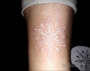 Фото тату на руке: белая снежинка, выполненная техникой white ink, выглядит нежно и загадочно на фоне кожи.