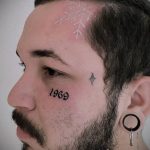 Фото татуировки снежинки на виске мужчины, рядом с датой '1969' и небольшим символом. Рисунок выполнен в минималистичном стиле.