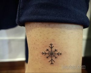 Фото небольшой татуировки снежинки на лодыжке. Рисунок выполнен тонкими черными линиями.