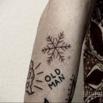 Фото тату снежинки и надписи "Old Man". Черно-белый рисунок татуировки, выполненный в минималистичном стиле, выглядит необычно и стильно.