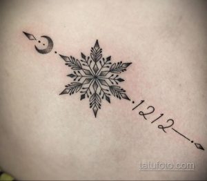 Фотография татуировки снежинки на коже, дополненной стрелой и датой '1212'. Изящный рисунок татуировки с символическим значением.