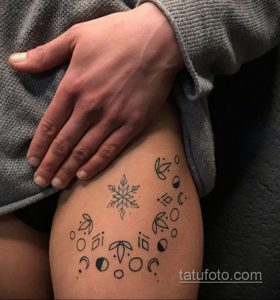 Фото тату с изображением нескольких снежинок и тонких веток на боку. Черно-белая татуировка в минималистичном стиле.
