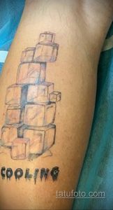 Фото необычной татуировки с изображением кубиков льда и надписью "Cooling". Стильный рисунок татуировки на руке.