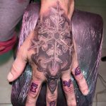 Фото тату снежинки и оленьей головы, выполненной в технике colorwork. Эскиз татуировки на руке.