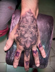 Фото тату снежинки и оленьей головы, выполненной в технике colorwork. Эскиз татуировки на руке.