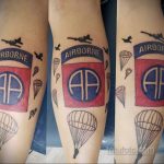 Фото татуировки с изображением парашютистов, самолета и надписи 'AIRBORNE' на руке. Цветная татуировка в стиле традиционный.