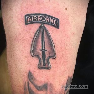 Фото тату с изображением ножа и десантного берета с надписью 'AIRBORNE' на руке. Черно-серая татуировка в реалистичном стиле.
