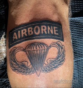 Фото тату парашюта с надписью 'AIRBORNE' на руке. Черно-белый рисунок татуировки в классическом стиле. Простой и лаконичный эскиз тату.