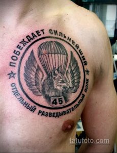 Фото татуировки с изображением волка в парашюте, заключенного в круг с военной символикой. Черно-серый рисунок с детальной проработкой.