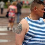 Фото старой татуировки на плече мужчины: изображение орла с раскрытыми крыльями и парашютом, выполненное в синих и черных тонах.