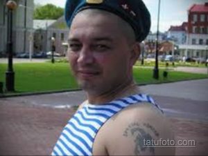 Фото тату на плече мужчины: воин в берете с татуировкой вертолета, выполненное в черно-белой гамме. Детализированный рисунок татуировки с военной символикой.