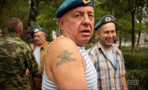 Фото тату на плече мужчины: воин в берете с вертолетом и надписью, выполненное в черно-белой гамме. Детализированный рисунок татуировки с военной тематикой.