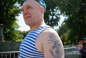 Фото тату на плече: воин в каске с черепом и вертолетом, выполненное в черно-белой гамме. Детализированный рисунок татуировки с элементами милитари.
