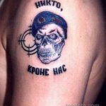 Фото татуировки черепа в берете ВДВ с надписью 'Никто, кроме нас'. Рисунок татуировки выполнен в черном цвете с элементами прицела.