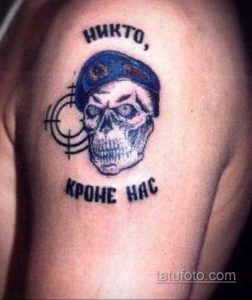 Фото татуировки черепа в берете ВДВ с надписью 'Никто, кроме нас'. Рисунок татуировки выполнен в черном цвете с элементами прицела.