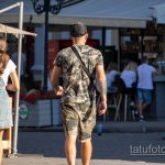 Фотография мужчины, идущего спиной вперед, с видимыми татуировками на спине, плечах и руках.