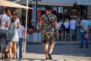 Фотография мужчины, идущего спиной вперед, с видимыми татуировками на спине, плечах и руках.